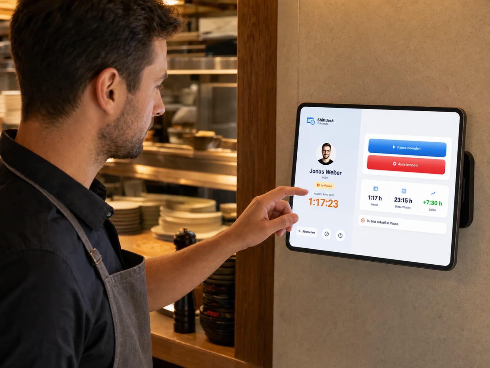 Männlicher Restaurantmitarbeiter bedient die echte Shiftdesk Tablet-Stempeluhr im Servicebereich